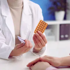 Lekarz pokazuje pacjentce opakowanie tabletek antykoncepcyjnych. Warto sprawdzić citrafleet cena.