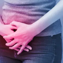 Osoba trzyma się za brzuch, odczuwając ból. Może to być objaw problemów, w leczeniu których pomaga Ditropan.