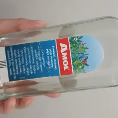 Dłoń trzyma butelkę Amolu. Ten lek, znany z dobrej ceny, zawiera mieszankę olejków eterycznych.