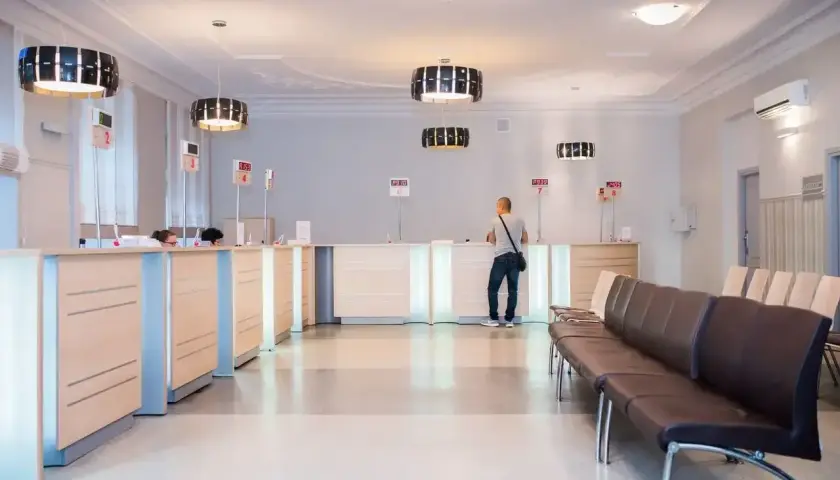 Recepcja w nowoczesnej klinice medycznej z poczekalnią i klientem przy ladzie.